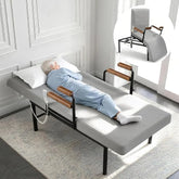 Elderly person lying on an electric adjustable floor bed with side safety rails in a bright bedroom.