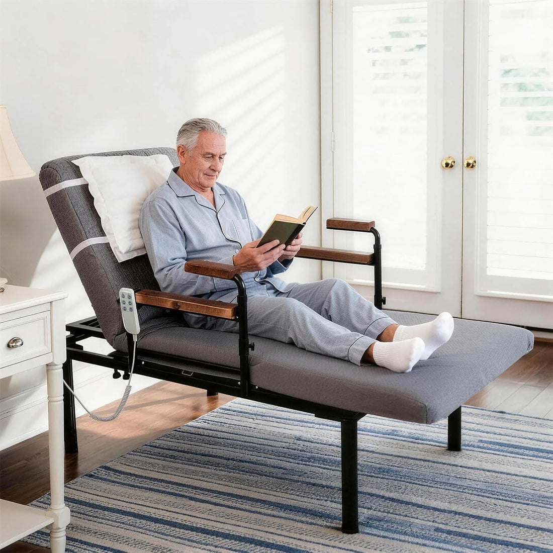 Elderly man reading while seated comfortably on the electric adjustable floor bed in reclined position.
